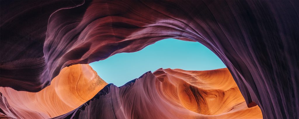 vue depuis une faille dans le canyon, roche aux couleurs brune à orangés qui contraste avec le ciel bleu, à Antelope Canyon, Etats Unis