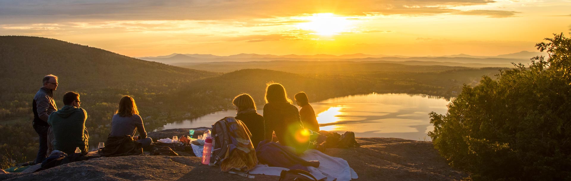 Groupe d'amis en pique nique devant un coucher de soleil