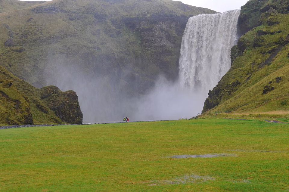 3 personnes face à l'immensité de la cascade skogarfoss, Islande