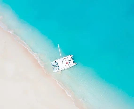 Catamaran sur une plage de sable blanc et eau bleu turquoise