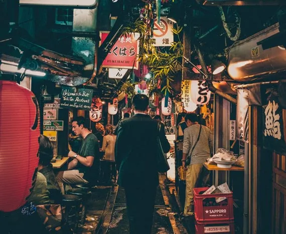 Homme marchant au milieu d'une rue remplies d'échoppes au Japon