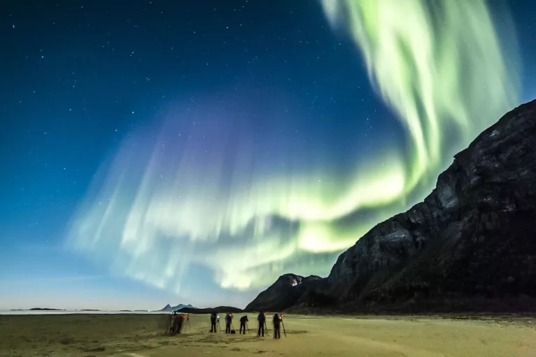 Aurores boréales lumineuse verte et violette dans le ciel nocturne au-dessus des montagnes, Norvège.