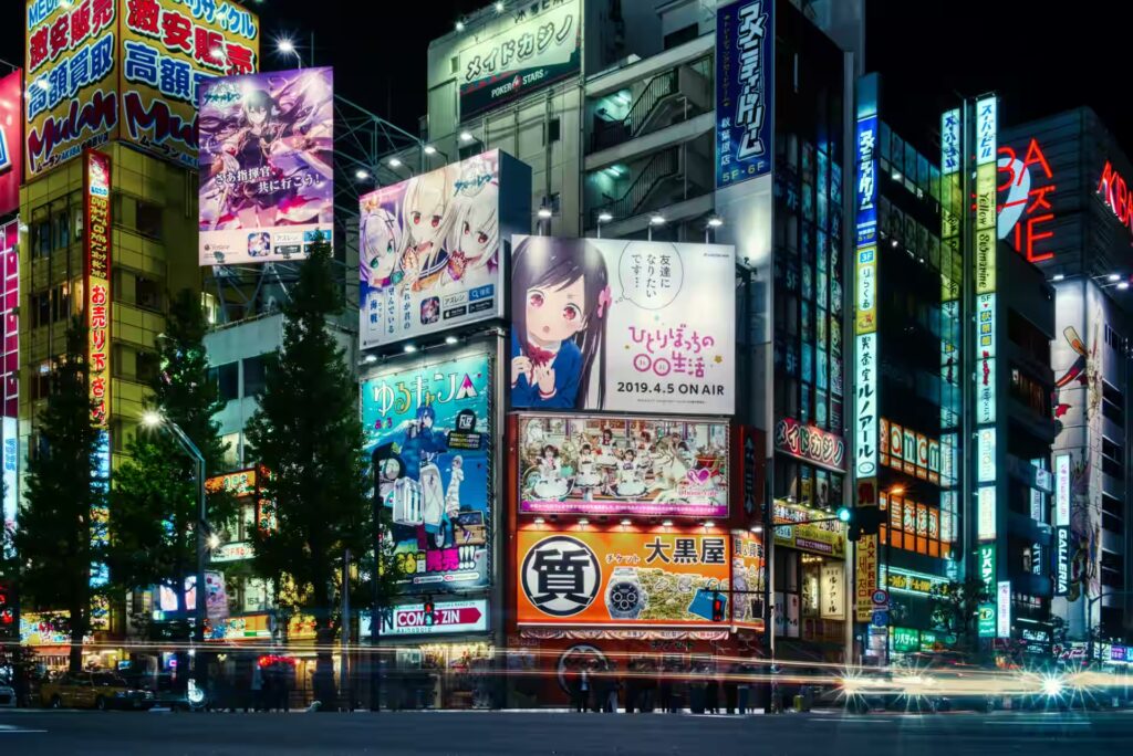 Rues animées bordées d’immeubles recouverts d’écrans et néons colorés, enseignes en japonais, ambiance urbaine de nuit, Akihabara, Tokyo, Japon.
