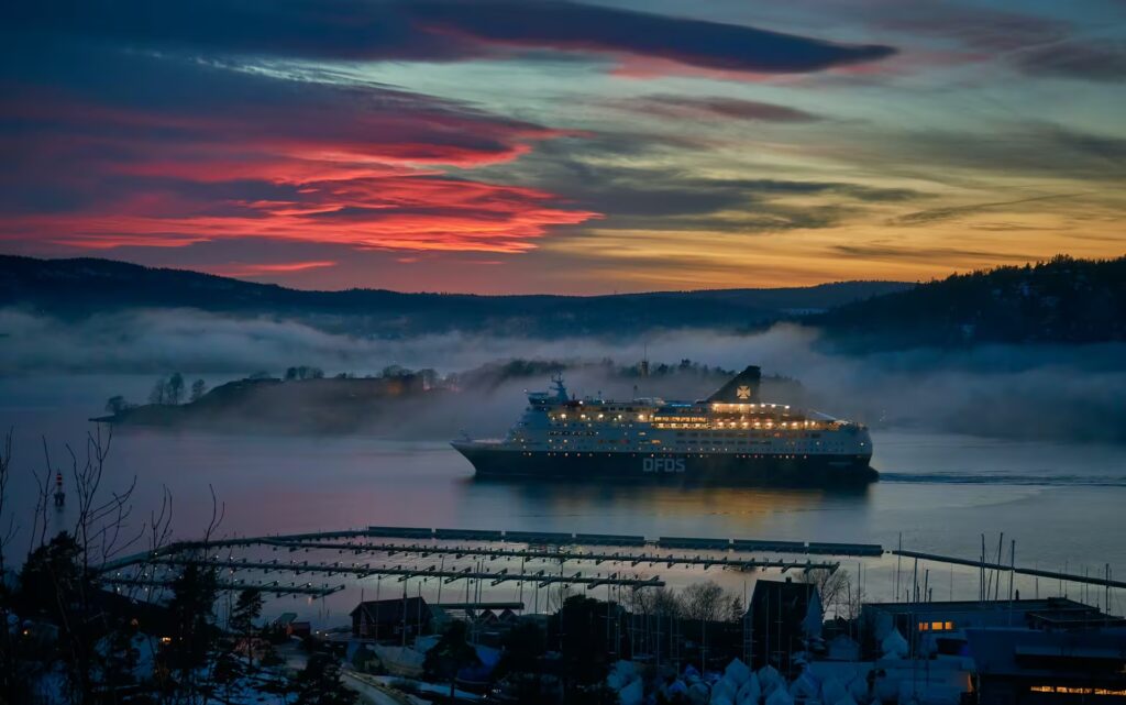 bateau de croisière dans un fjord en Norvège , devant un coucher de soleil Norvège 