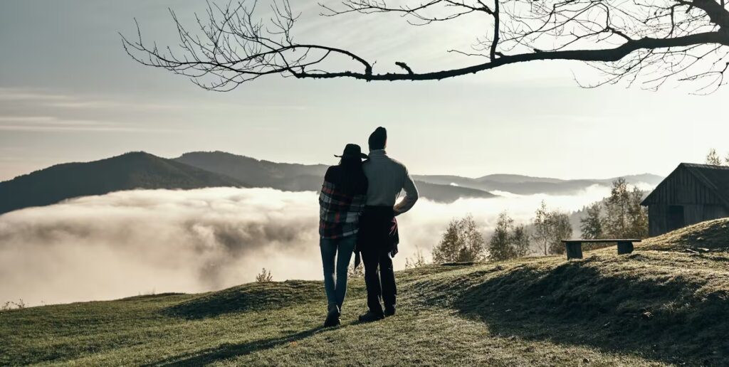 Couple dans la nature, devant un paysage de montagne dans les nuages