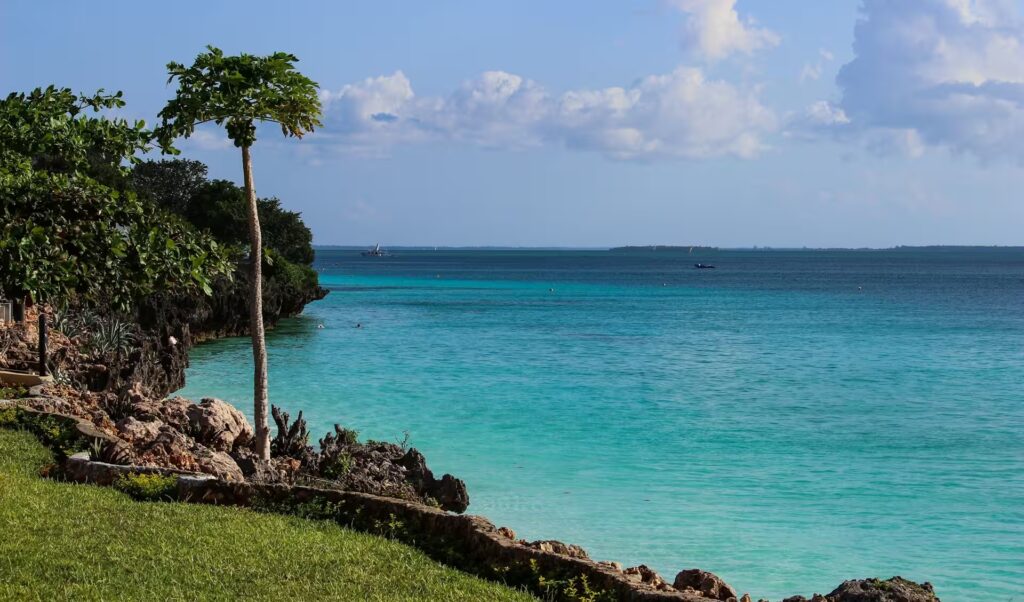 Plage de sable blanc bordée d’eaux turquoise à Zanzibar, en Tanzanie, sous un ciel bleu éclatant.