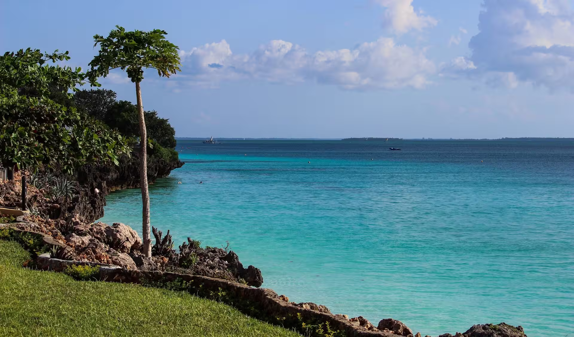 Plage de sable blanc bordée d’eaux turquoise à Zanzibar, en Tanzanie, sous un ciel bleu éclatant.