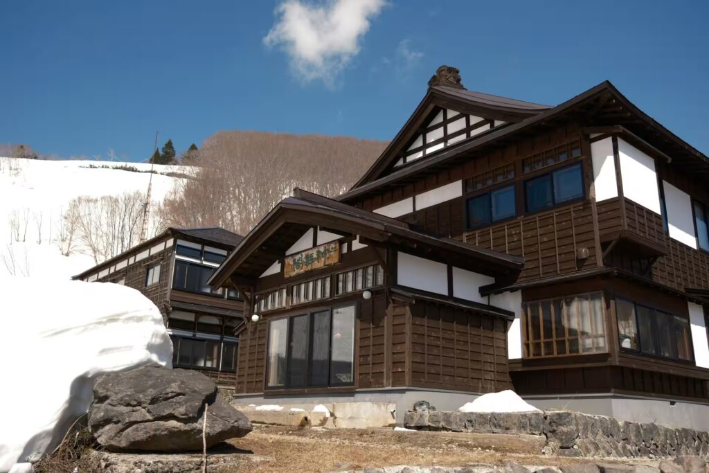 Ryokan traditionnel japonais dans un paysage de montagne enneigé.