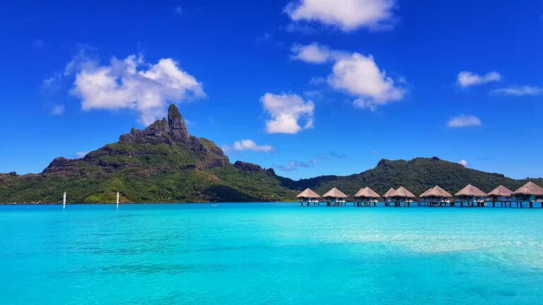 Bungalows sur pilotis sur le lagon turquoise de Bora Bora, avec le Mont Otemanu en arrière-plan, en Polynésie française.