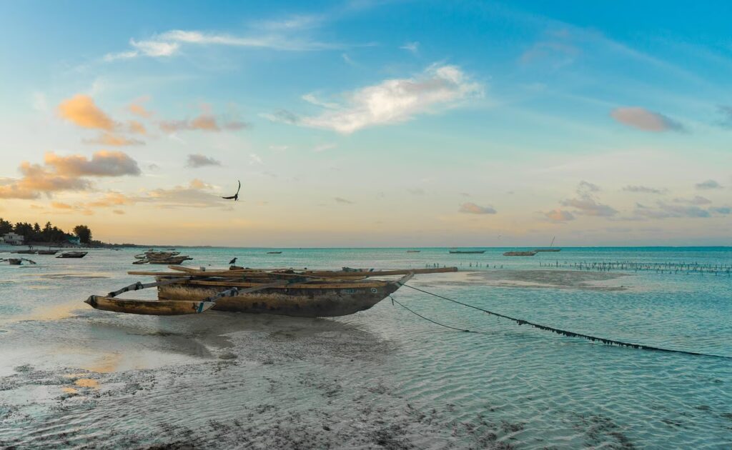 Boutres traditionnels en bois (dhows) sur une plage de sable blanc aux eaux turquoise à Zanzibar, Tanzanie.
