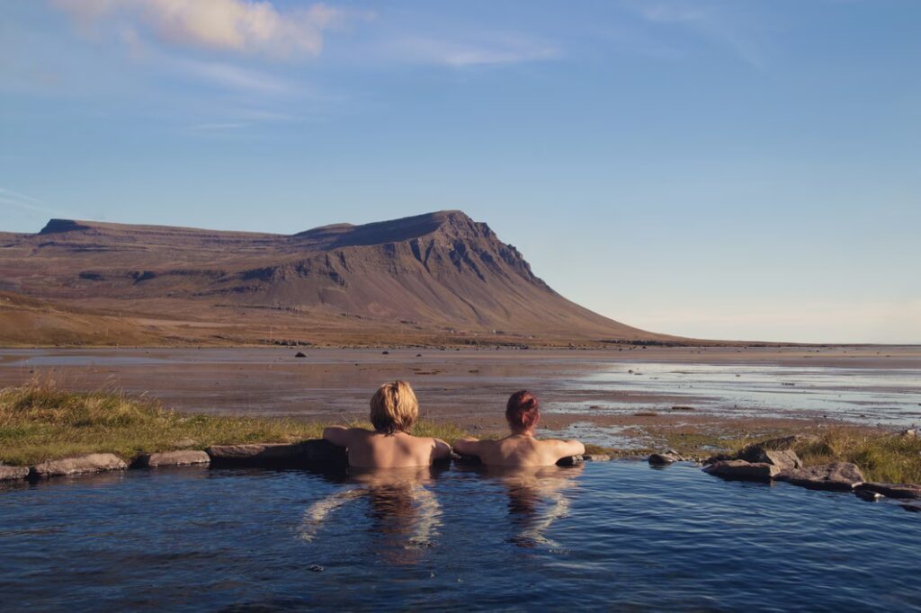 couple dans un bain chaud naturel géothermique de Krosslaug avec vue spectaculaire sur la nature islandaise en arrière-plan, Birkimelur
