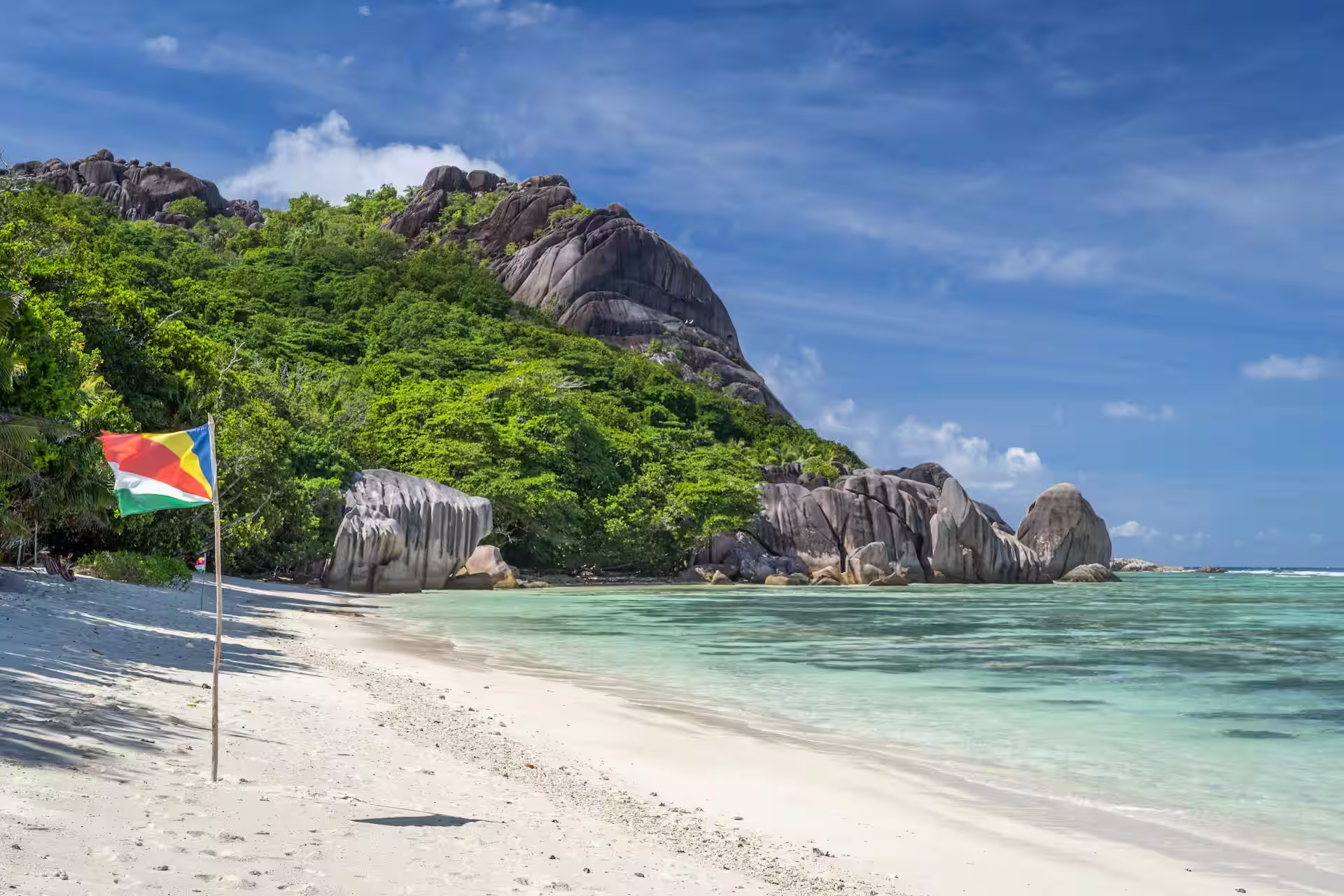 Plage avec montagnes en fond et drapeau des Seychelles