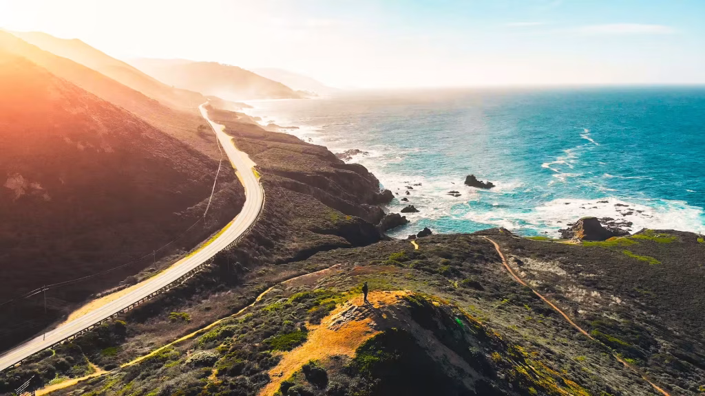 Vue aérienne d'un coucher de soleil d'une route entre des montagnes et la mer en Californie, Amérique de l'ouest