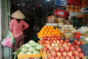 Une femme debout devant un stand de fruits dans un marché à Hô Chi Minh, Vietnam