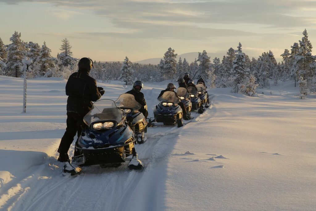 Groupe en motoneiges dans paysage enneigé, Laponie, Finlande