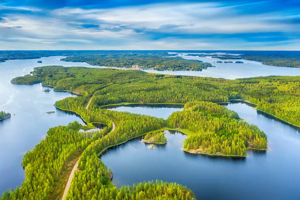 Vue aérienne de route entre la forêt verte d'été et les lacs bleus, région des lacs, en Finlande