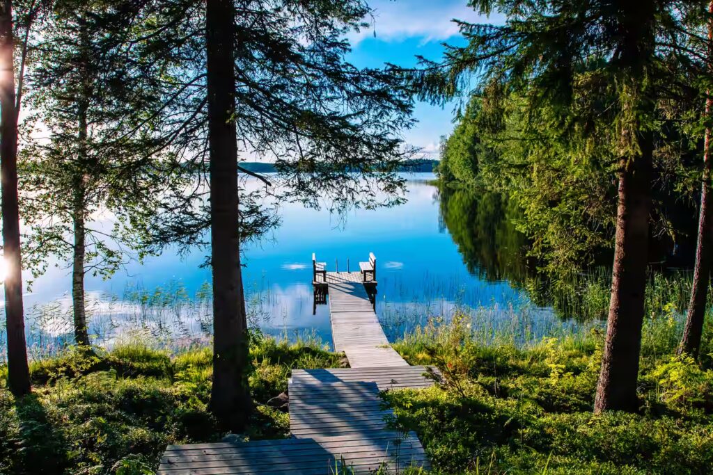 Jetée en bois avec banc pour se reposer sur un lac bleu entouré de forêt, en Finlande