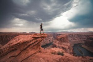 Homme debout au sommet d'une falaise avec vu sur le Horseshoe Bend, Colorado