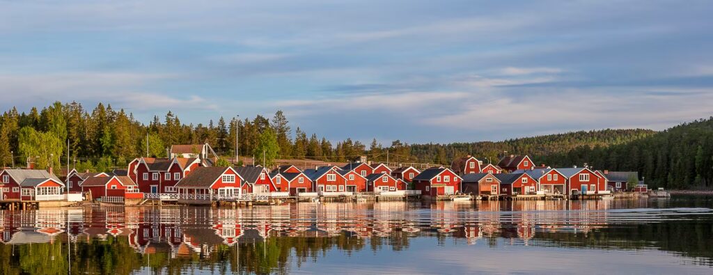 Village avec des maisons en bois rouges au bord d'un lac, en Suède