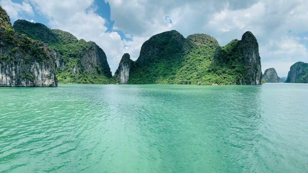 Collines pains de sucre recouverts de végétation sur une mer aux eaux vertes dans la baie d'Halong, Vietnam