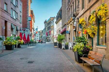 rue pavée de vieux batiments, coloré de plantes et fleurs, bannieres, chaises et banc, canada