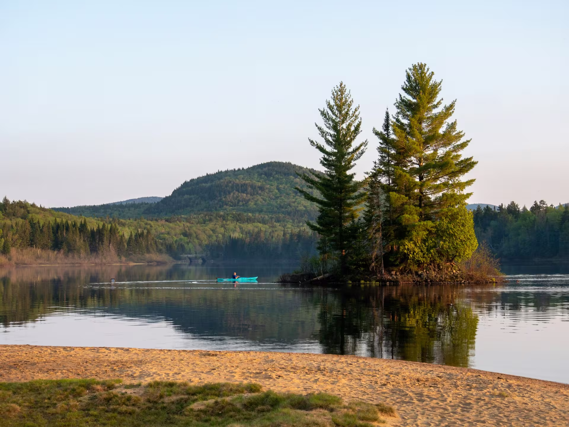 lac entouré de végétation et sapins, personne faisant du kayak, canada