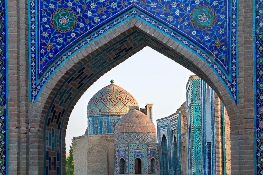 Vue sur les mausolées et les dômes du cimetière historique de Shahi Zinda par une porte voûtée, Samarcande, Ouzbékistan