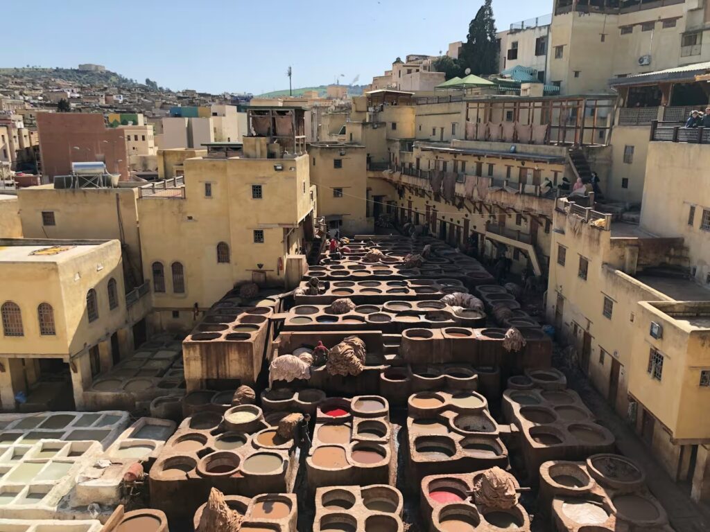 Plusieurs petits bassins remplie de liquide colorés, du line à côté au couel de la ville
