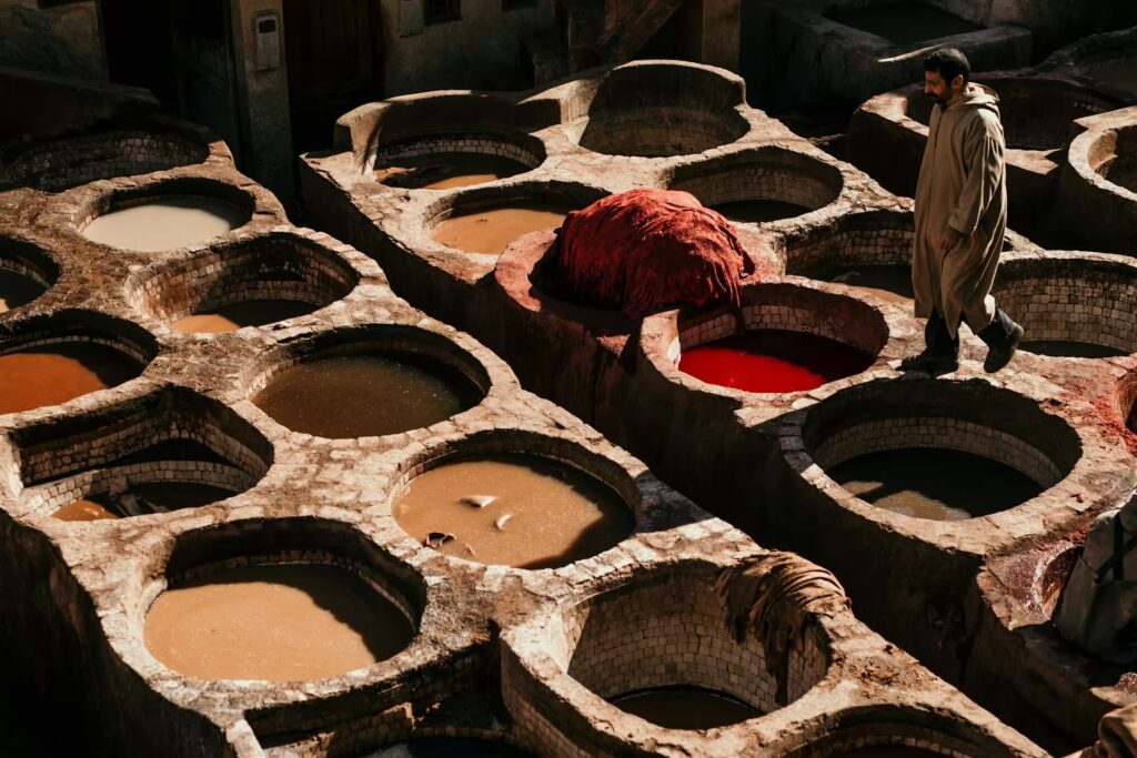 Plusieurs petits bassins remplie de liquide colorés, du line à côté au couel de la ville avec un homme qui passe entre