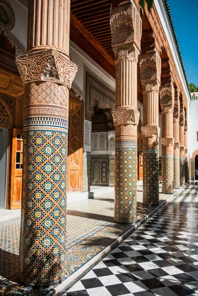 Carrelage damier noir et blanc, colonne décorées de mosaïques et gravées ainsi que le batiment avec porte en bois