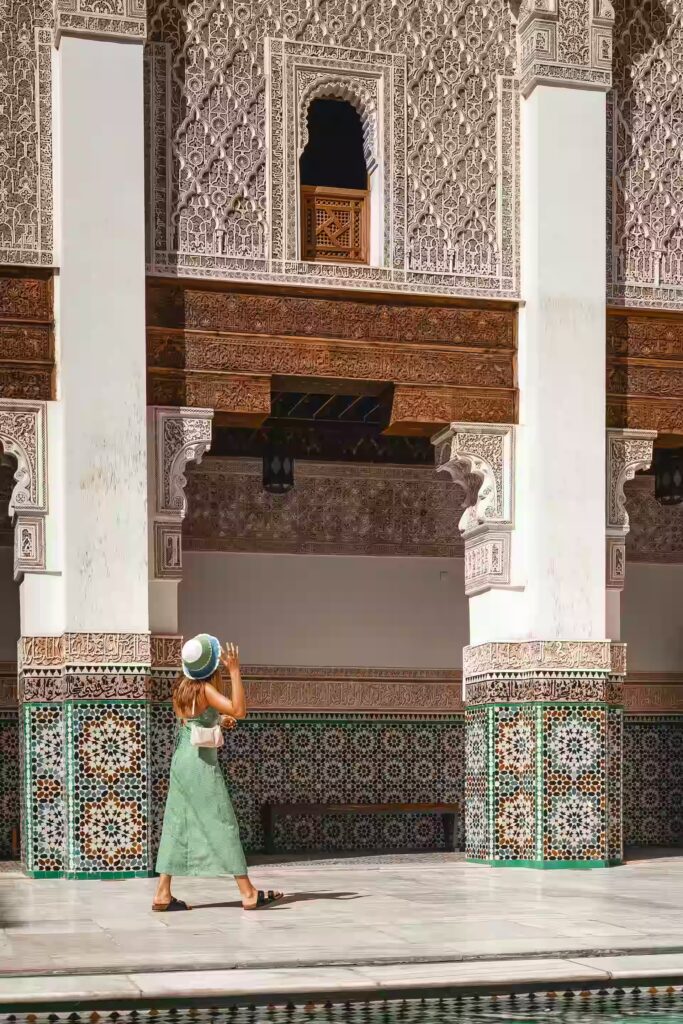 Femme passant devant un mur et arcades décorées de mosaïques et de gravures