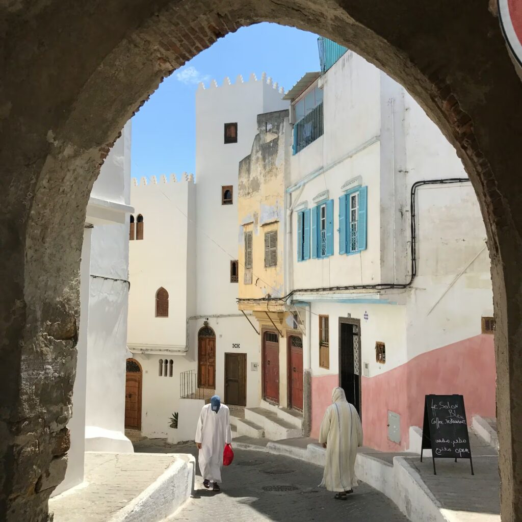 Ruelle pavée descendante avec deux personnes et batiments blancs