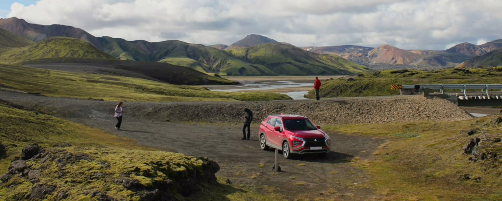 Voyageurs près de leur voiture, devant vaste paysage de collines et monts verdoyants en Norvège