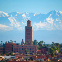 Tour et toits de la medina de Marrakech, avec les montagnes de l'Atlas en arrière plan, Maroc