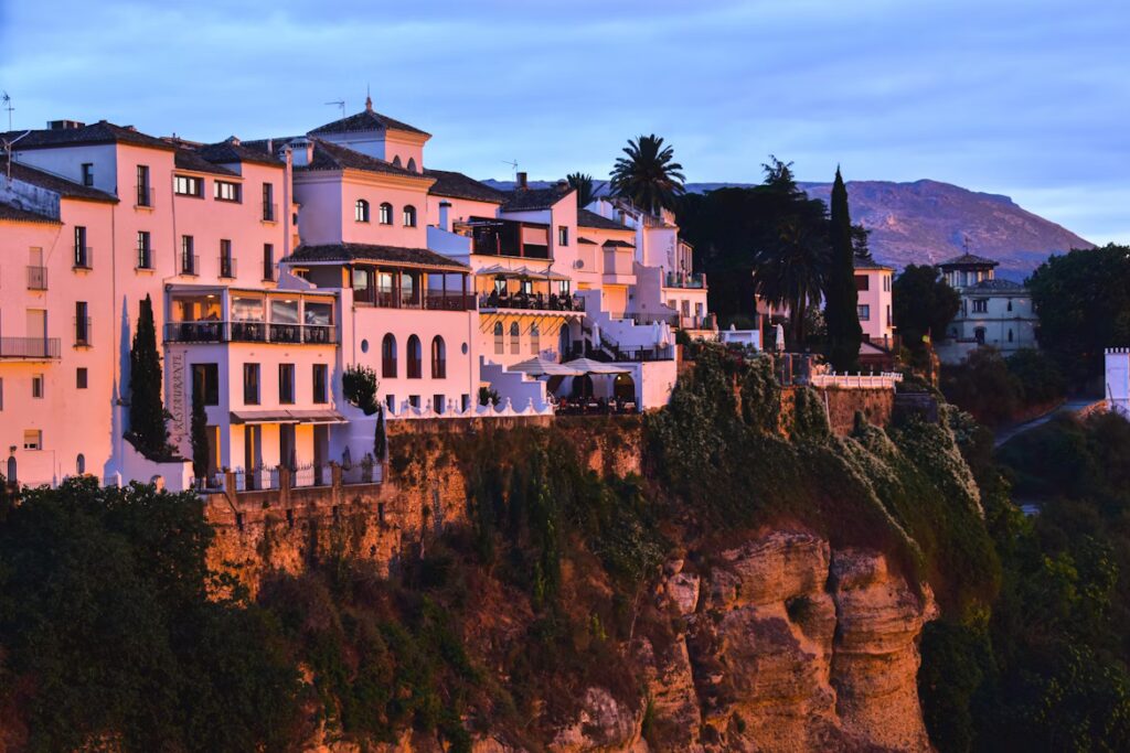 Immeubles et maisons balanches à flanc de falaise avec vegetation au coucher du soleil