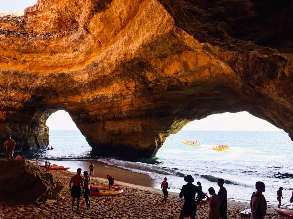 Formation rocheuse au dessus d'un plage avec personnes et petits bateaux