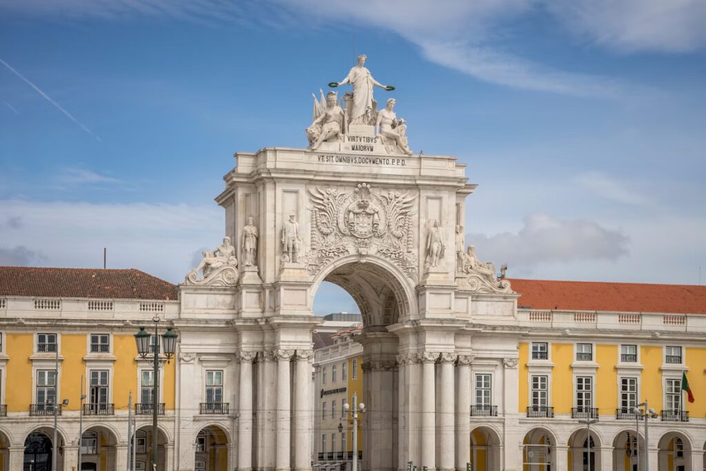 Batiments jaune avec arcades relié par une arche décorées de scupltures