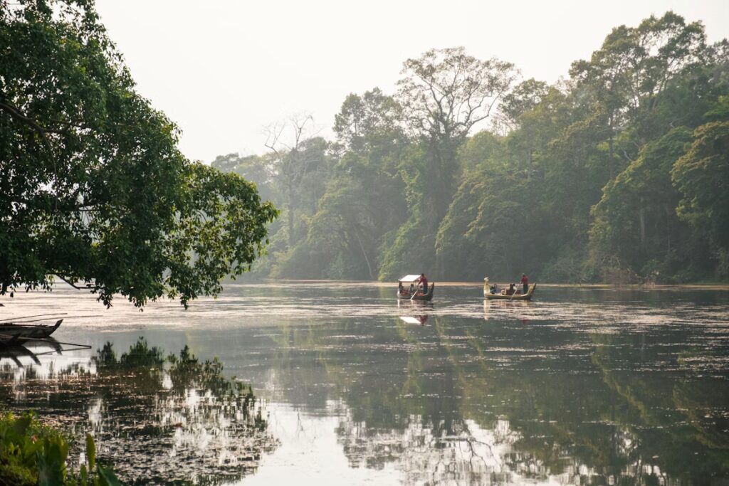 Fleuve bordé de végétation, barques avec quelques personnes