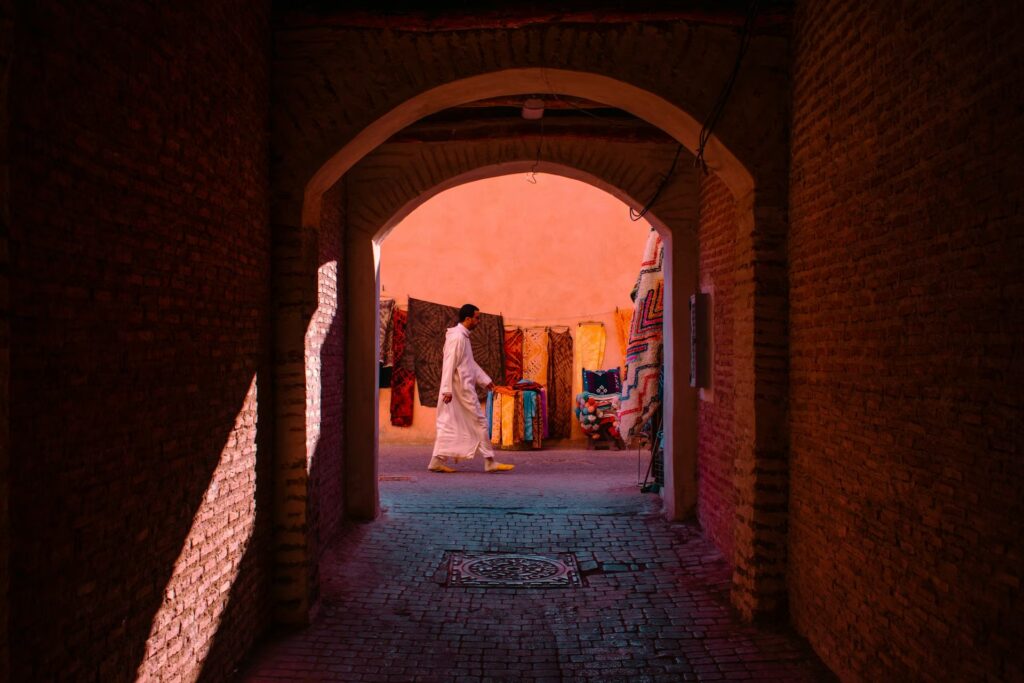Rue et murs pavés, tunnel, tissus colorés suspendu et pliésle lond d'un mur orange et passant dans la rue