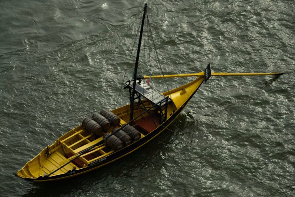 Bateau jaune sans voile avec gouvernail manuel et barils en bois dessus, sur l'eau