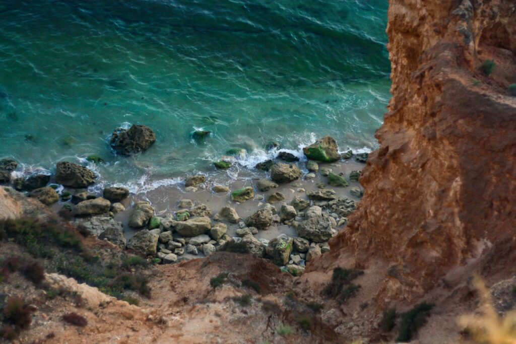 Vue d'une falaise vers le bas où on voit la mer et quelques rochers et roches
