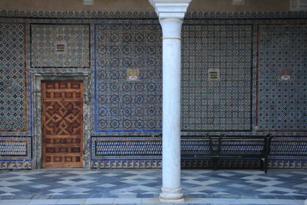 Mur de mosaique avec motifs, carrelage blanc et bleu, porte en boix et colonne blanche