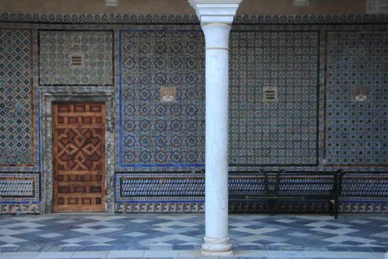 Mur de mosaique avec motifs, carrelage blanc et bleu, porte en boix et colonne blanche