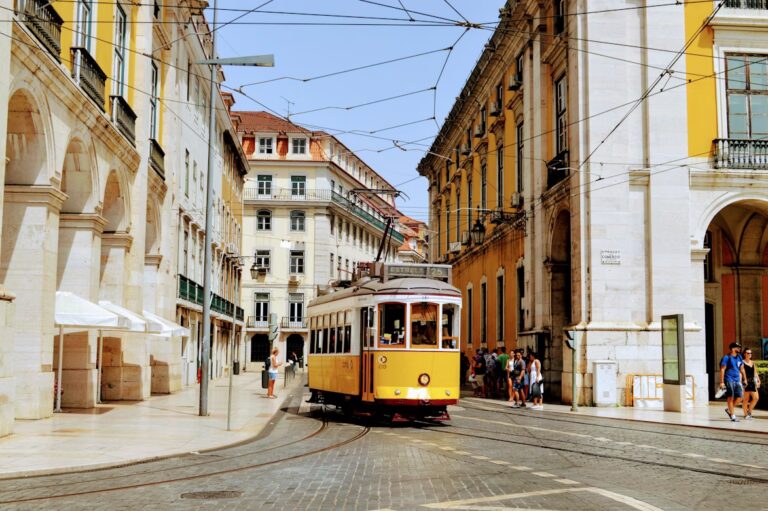 Tram jaune et blanc, dans les rues pavées aec batiments colorés