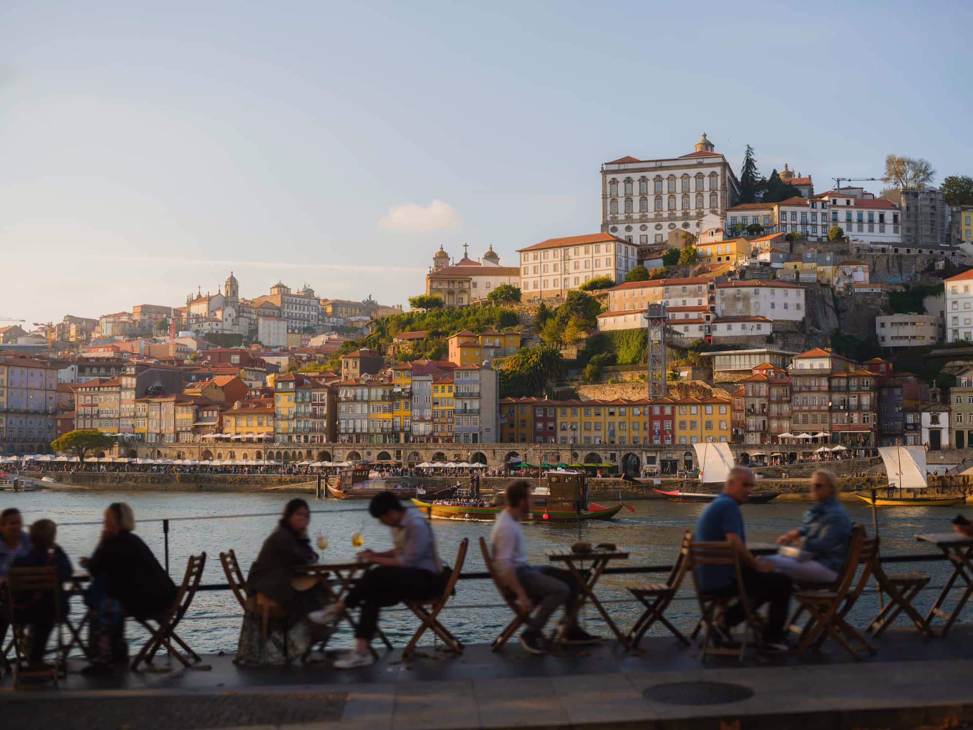 Foule en terrasse d'un restaurant au bord du fleuve, avec la ville de Porto en arrière plan, Portugal
