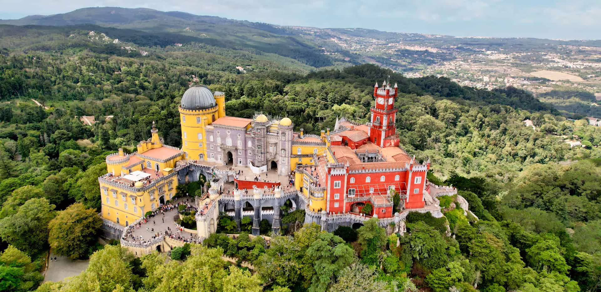 Vue aérienne d'un chateau coloré, jaune et rouge, qui émerge de la végétation, Sintra, Portugal