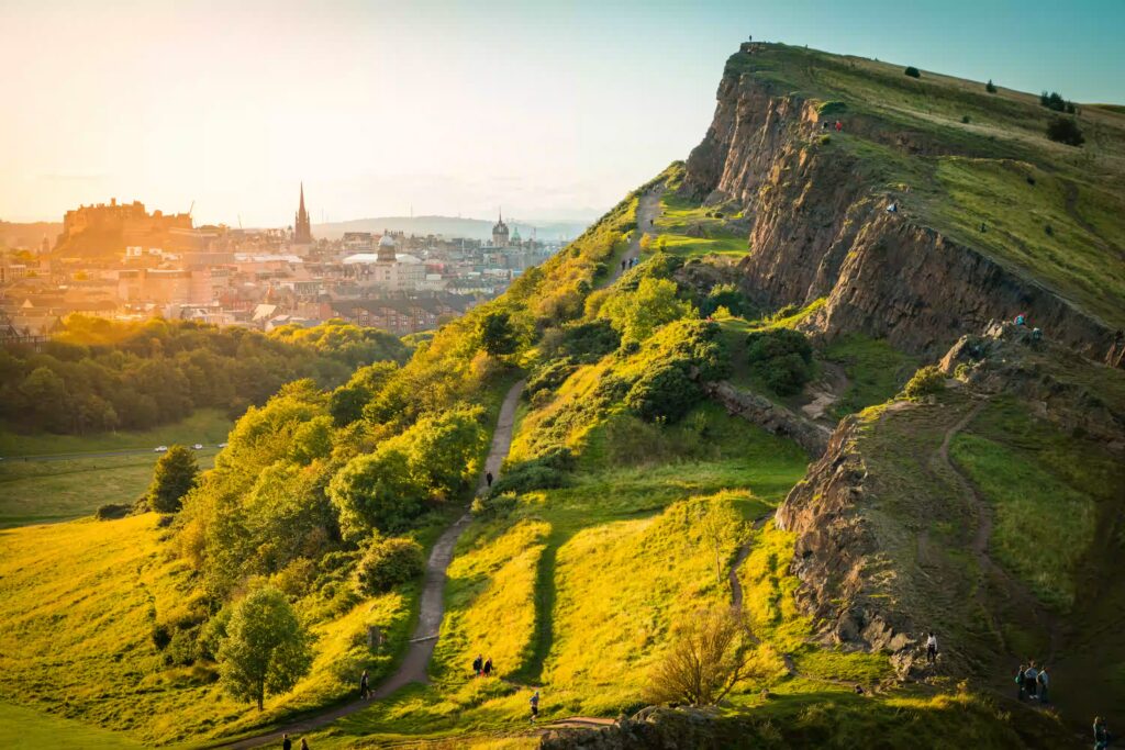 Montagne avec chemin pedestre, lumiere du soleil de fin de journée, ville en fond