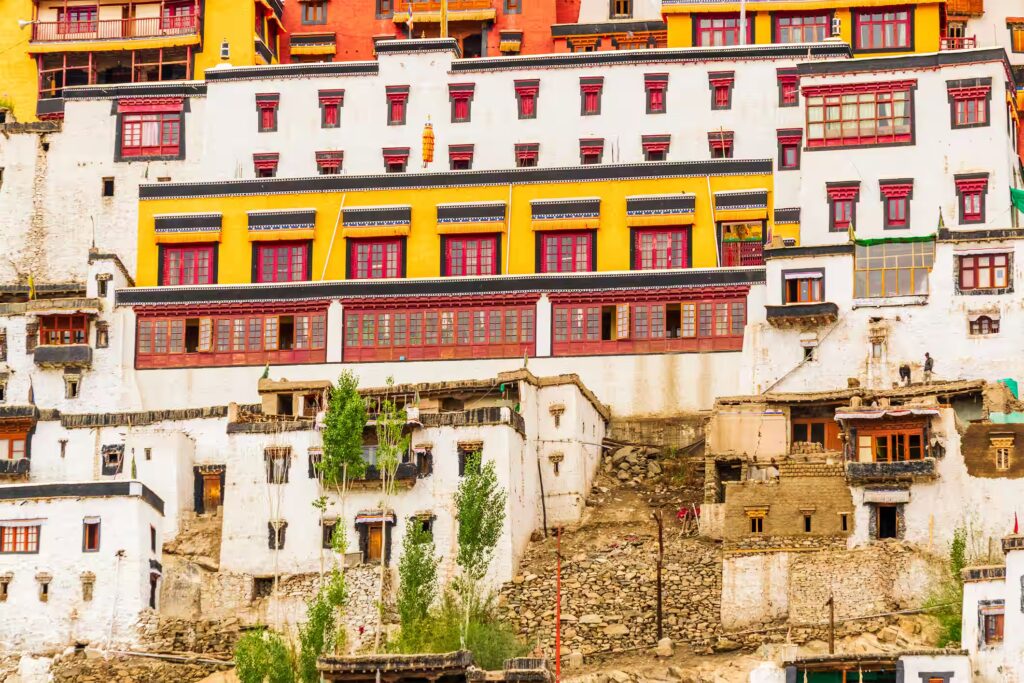 Façades de maisons et batiments blanc, rouge et jaune constuit en pente, avec une peu de végétation