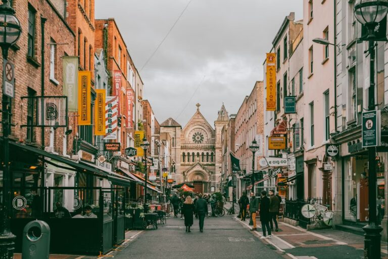 Rue piétonne avec façade d'une eglise au fond et rue bordée de commerses avec pancartes accrochées aux façades