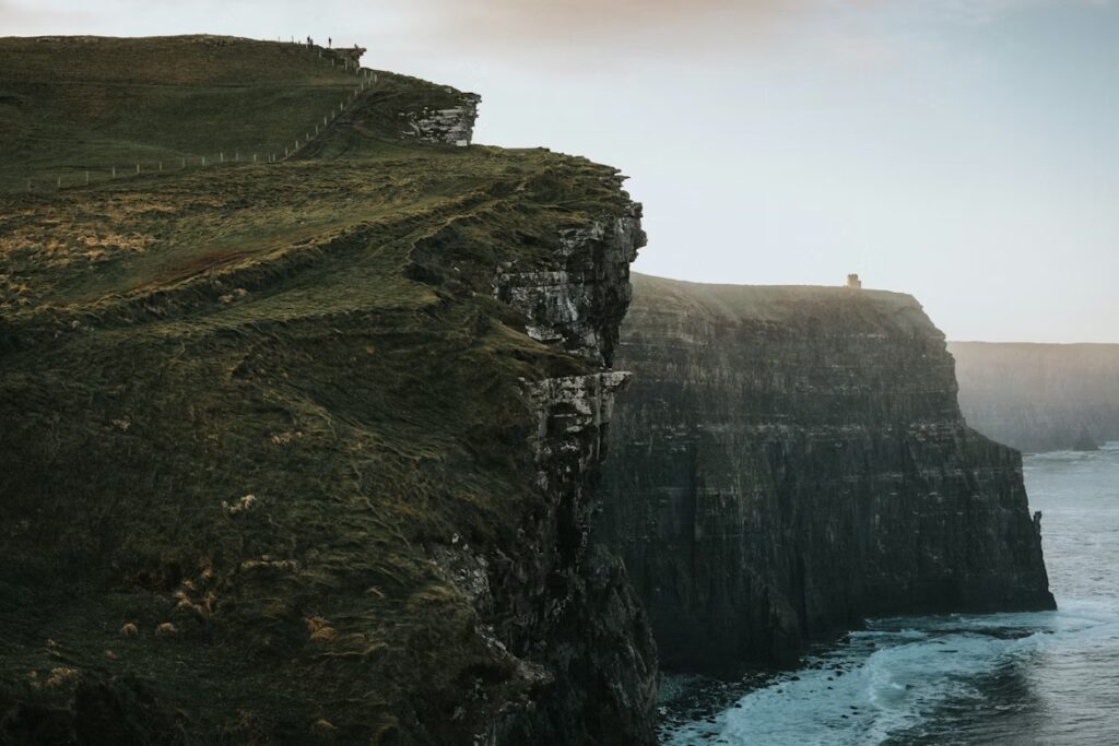 mer au pied la falaise, dont une partie est en pente, petit batiment au loin
